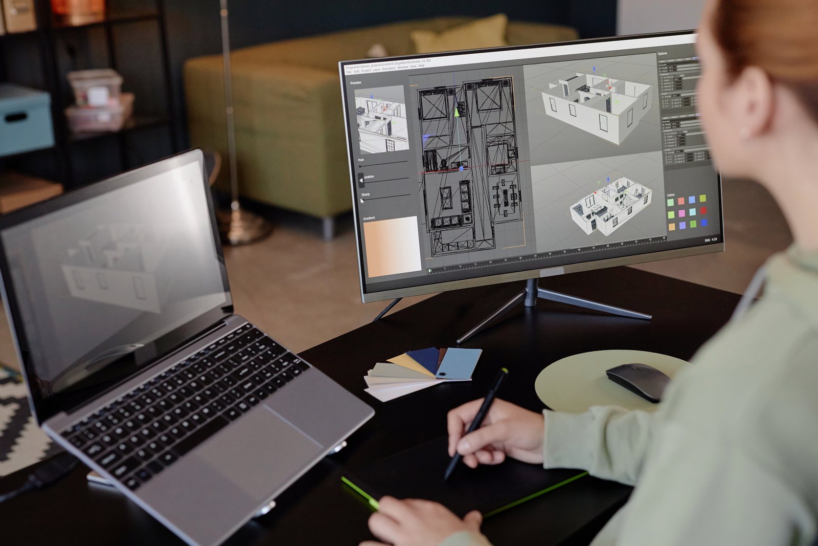 Person sketching beside a monitor showing an architectural floor plan and 3D model