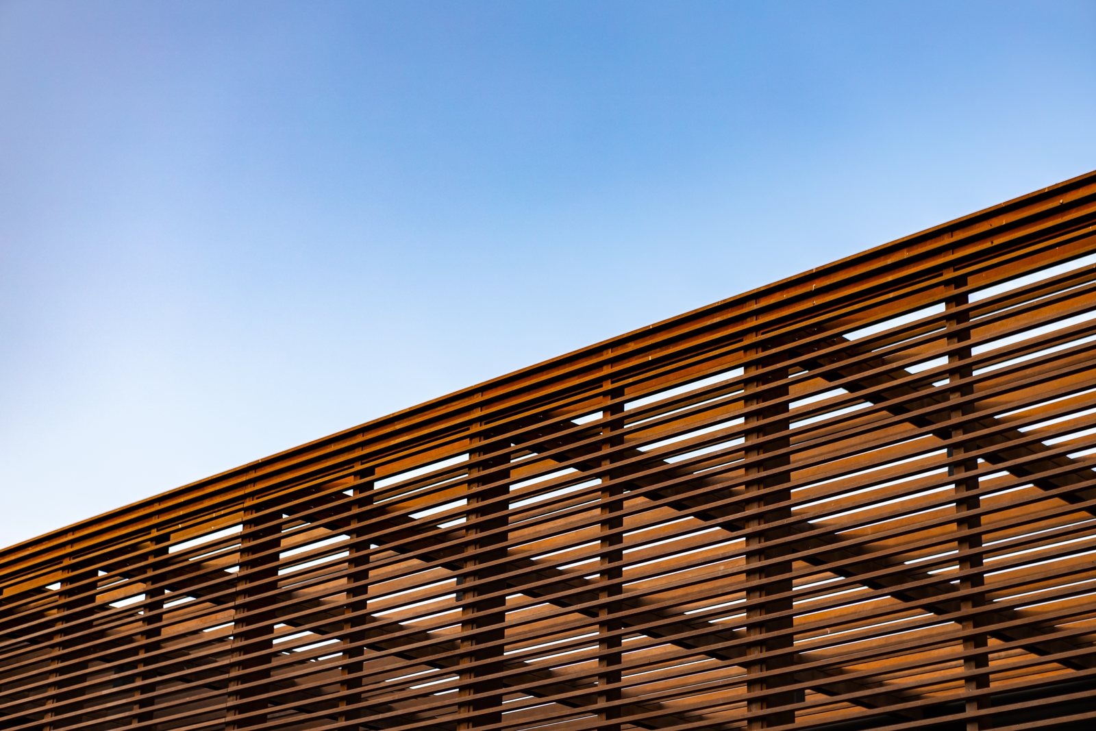 Wooden slat shading structure against a blue sky