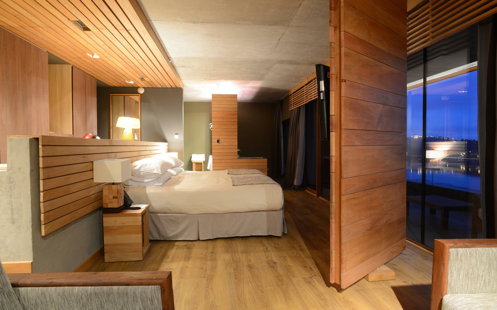 Hotel guest room with wood-panelled casegoods and a night view through the window