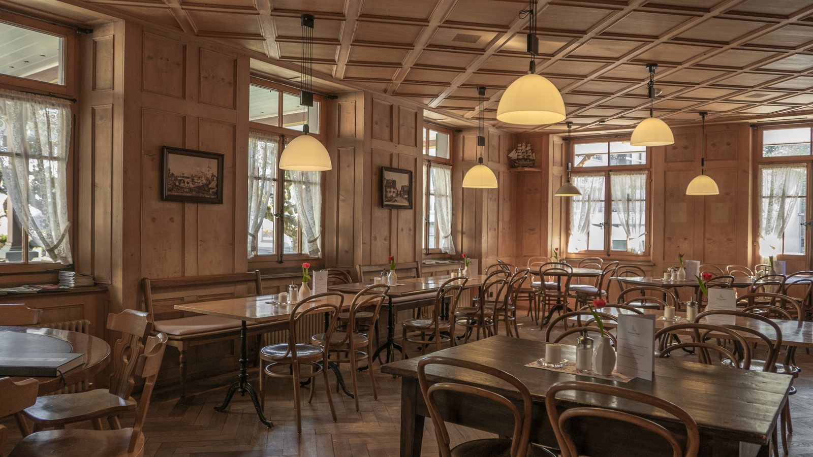 Restaurant dining room with wood tables, chairs and pendant lighting