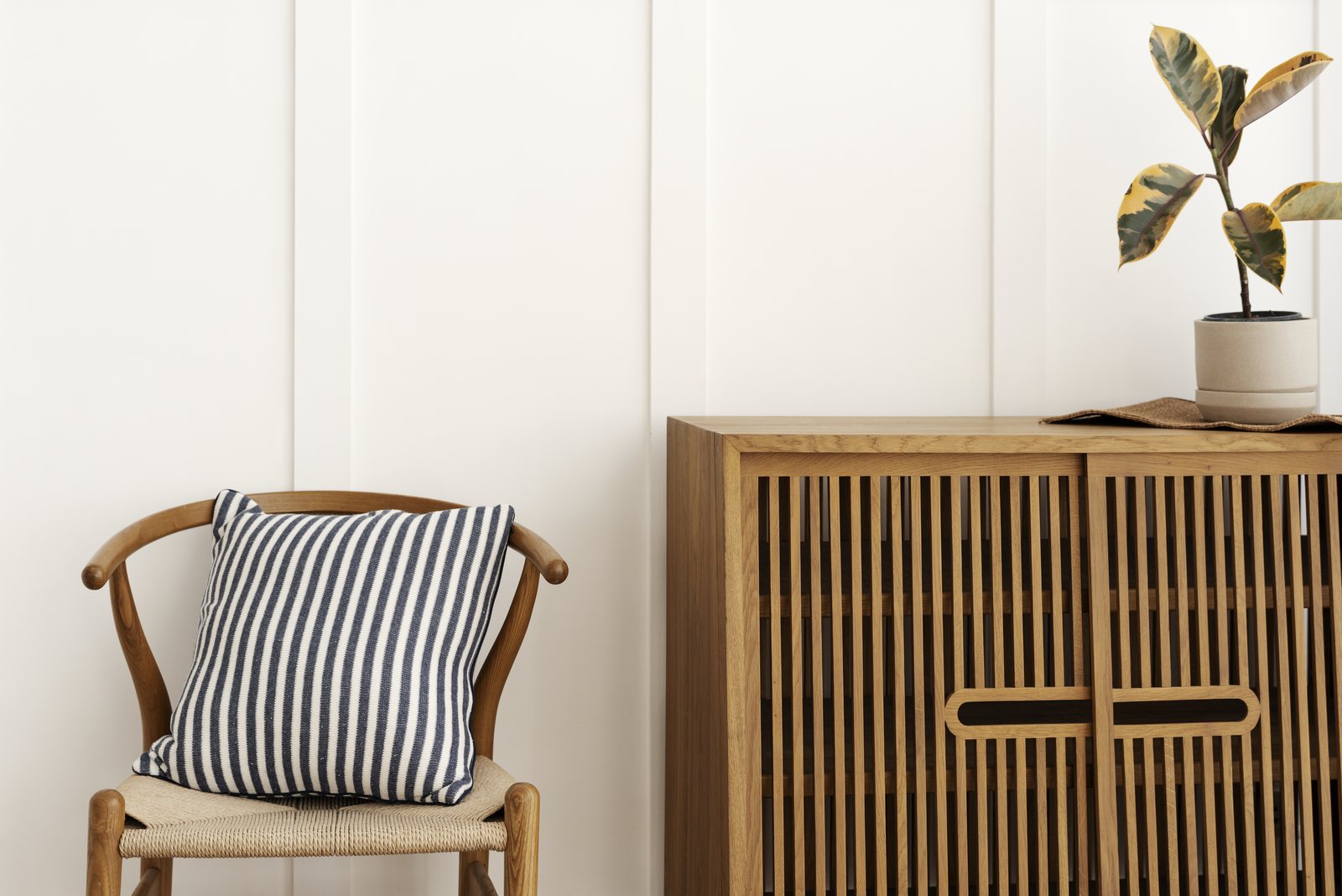 Wood sideboard cabinet beside a chair with a striped cushion