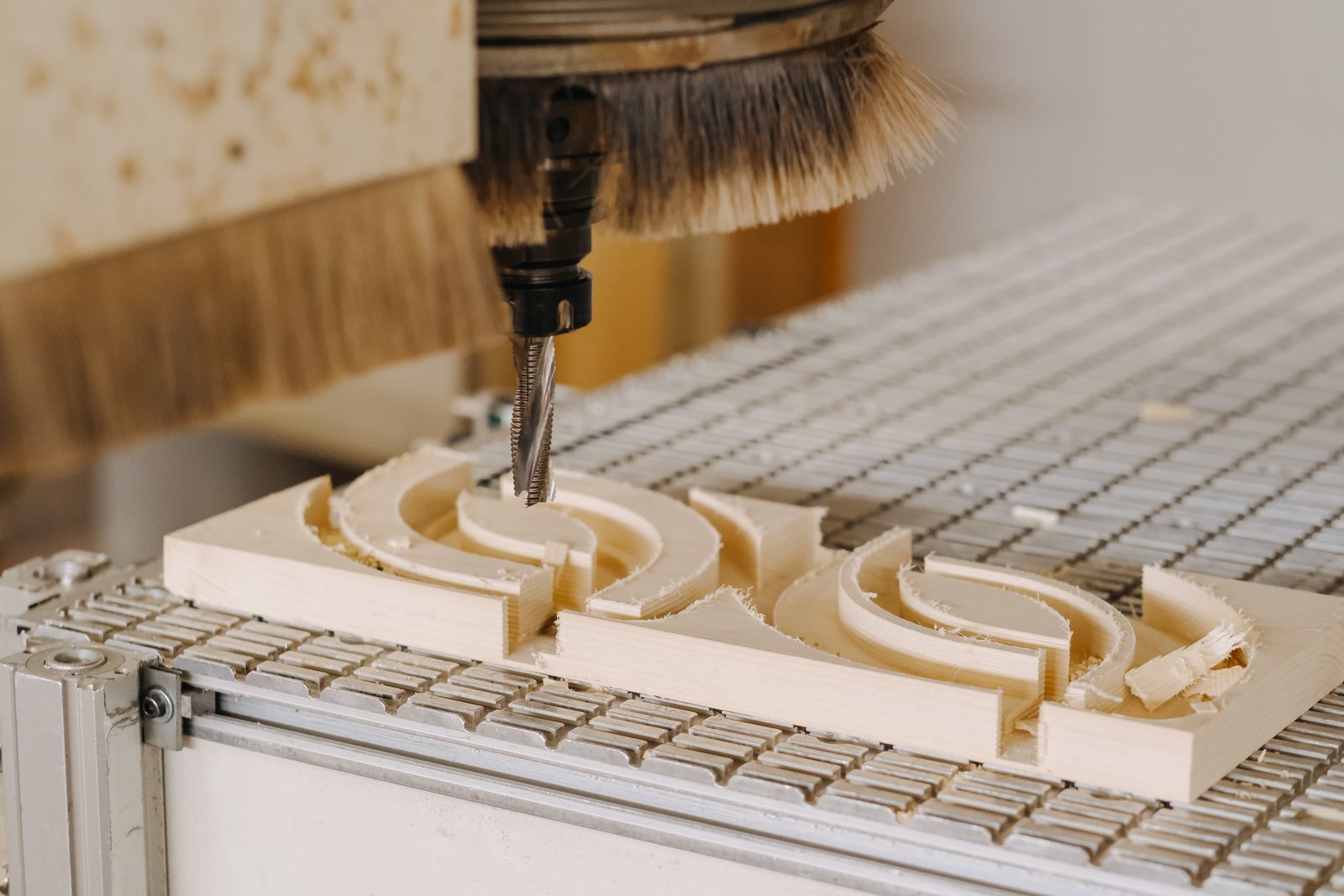 CNC bit carving curved recesses into a wood plank, close up