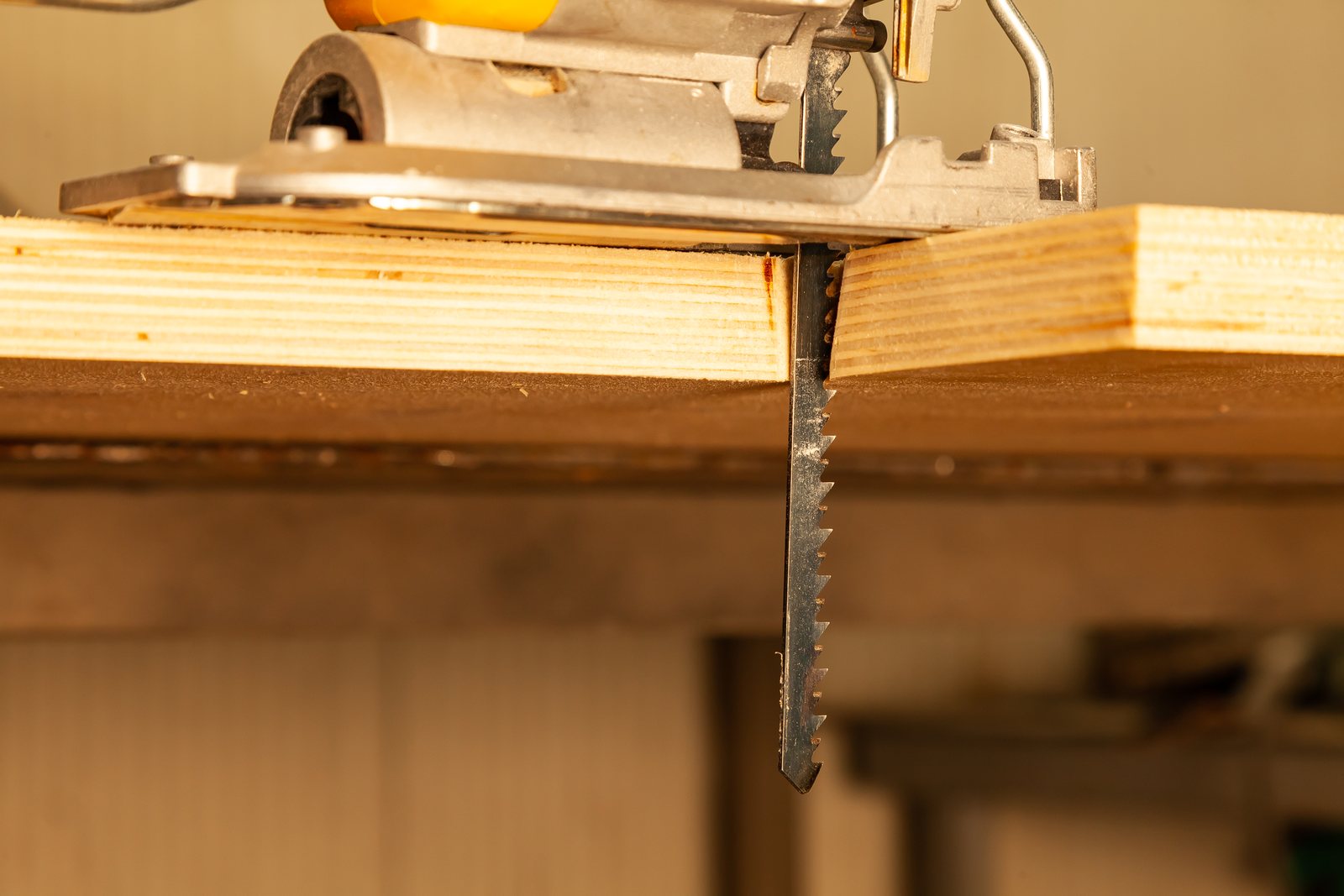 Yellow jigsaw resting on a workbench beside cut sawn wood