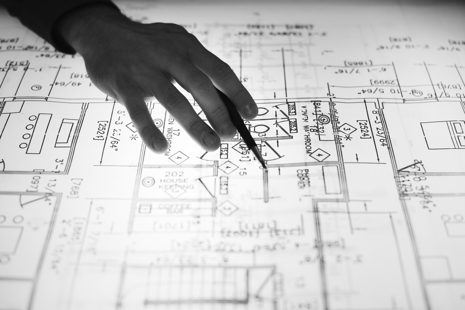 Hand pointing a pencil at a floor plan showing washroom and room labels