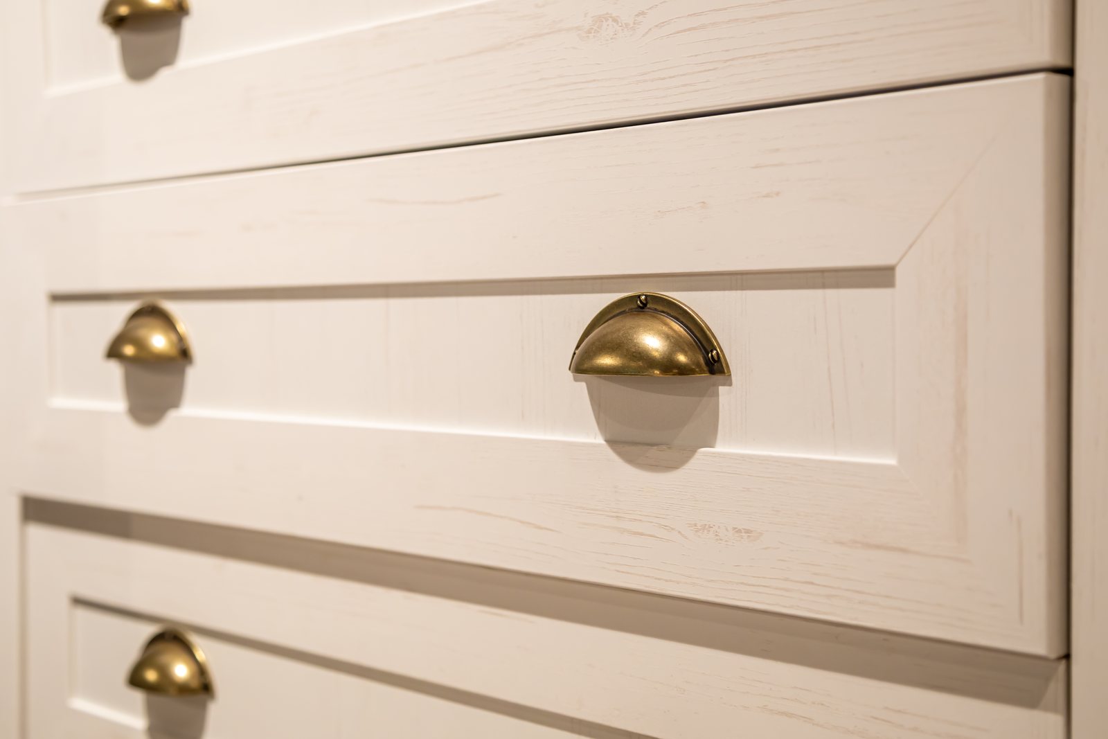 Close-up of brass cup pulls set into wood drawer fronts