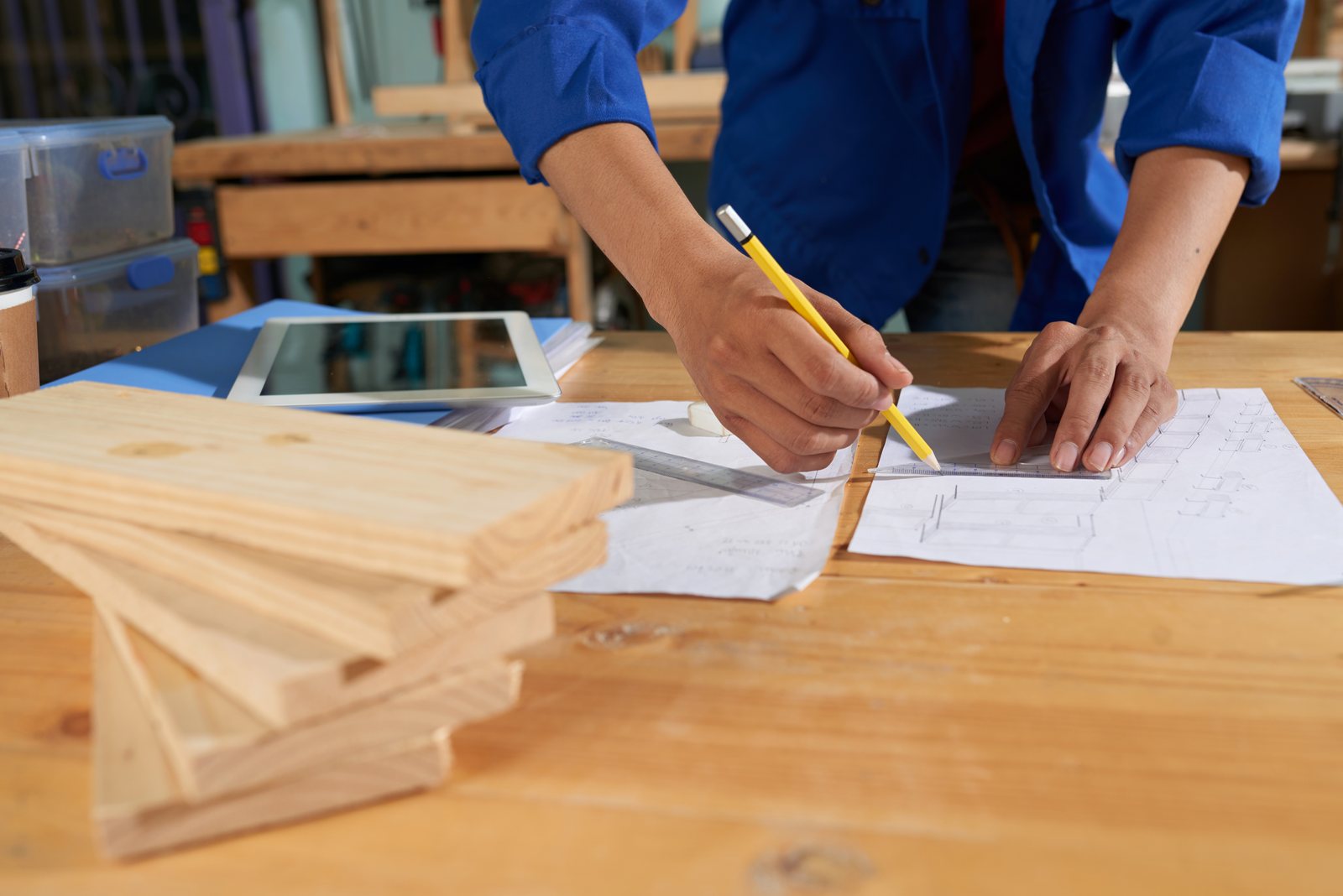 Worker marking up a furniture sketch on paper at a workbench