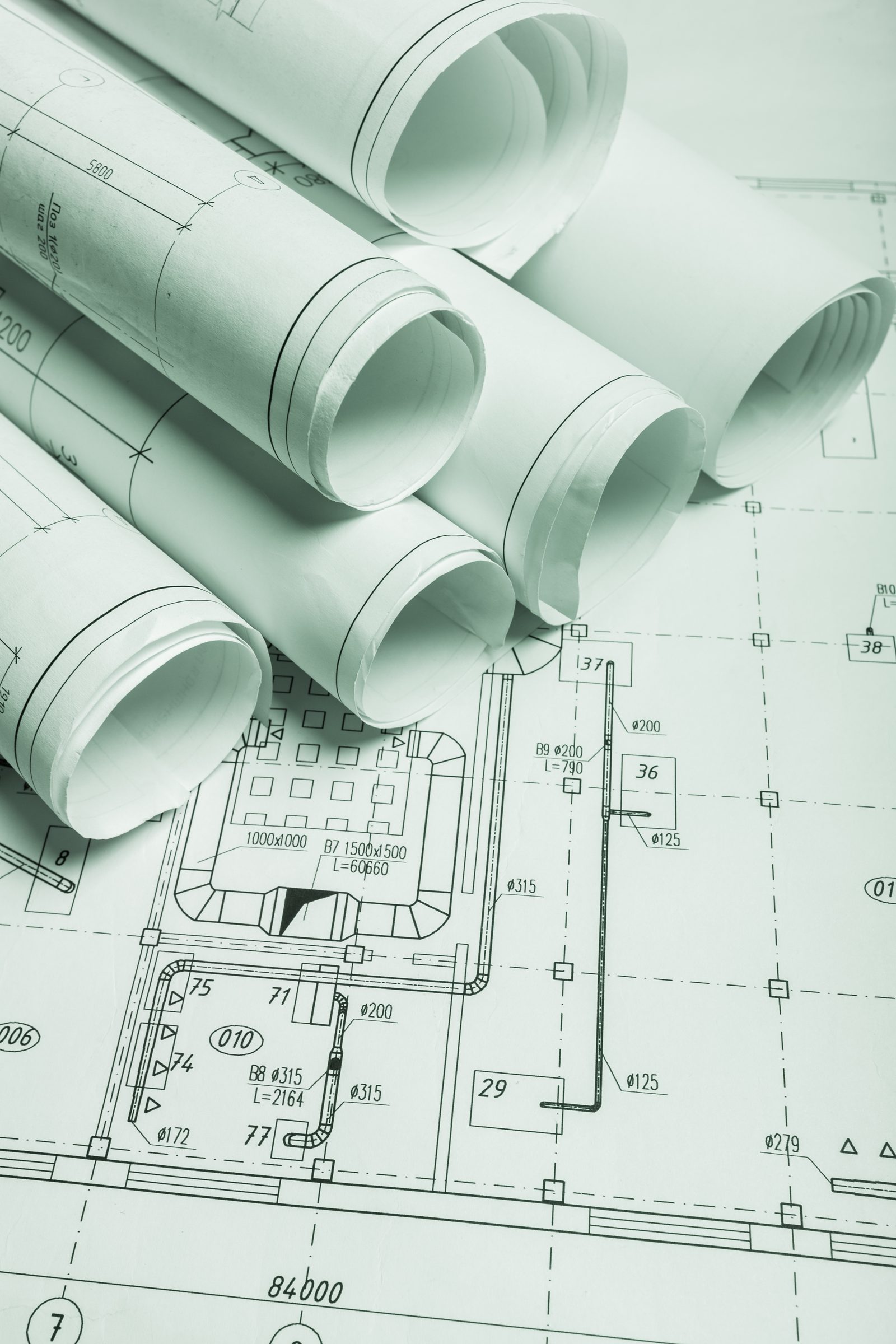 Rolled mechanical and architectural drawing sheets in green-toned lighting