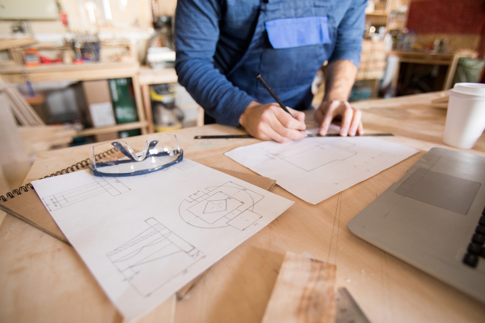 A woodworker sketching a construction detail by hand at a workbench